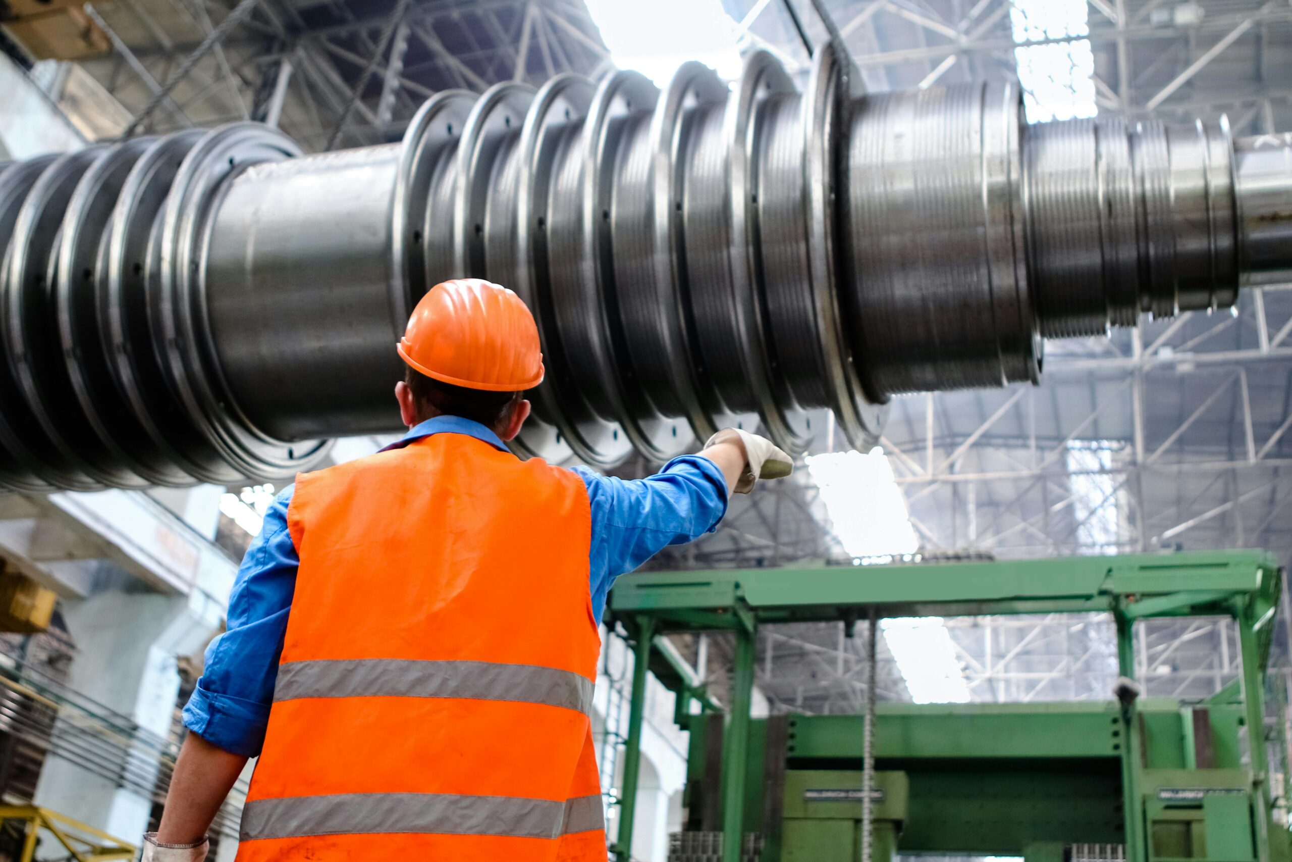 Worker seen from behind beside industrial machinery